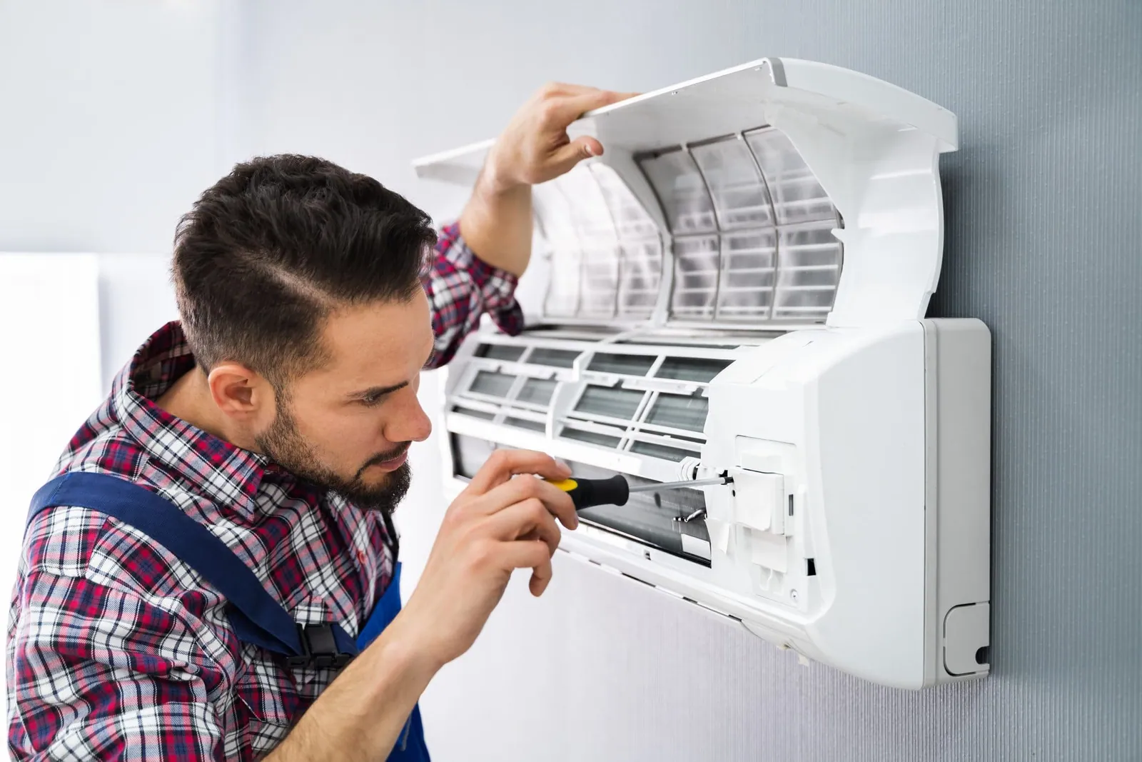 Técnico limpiando el filtro de un split durante una reparación de aire acondicionado