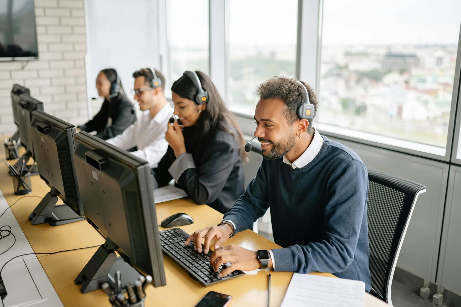 Equipo de atención al cliente con auriculares en una oficina luminosa