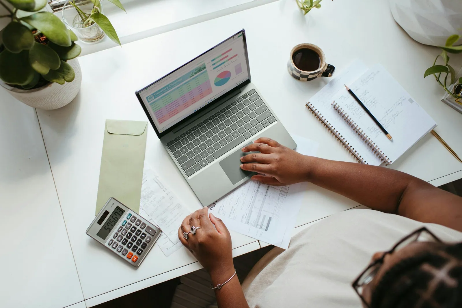Mesa de trabajo con portátil, calculadora y notas para revisar el alta de un profesional