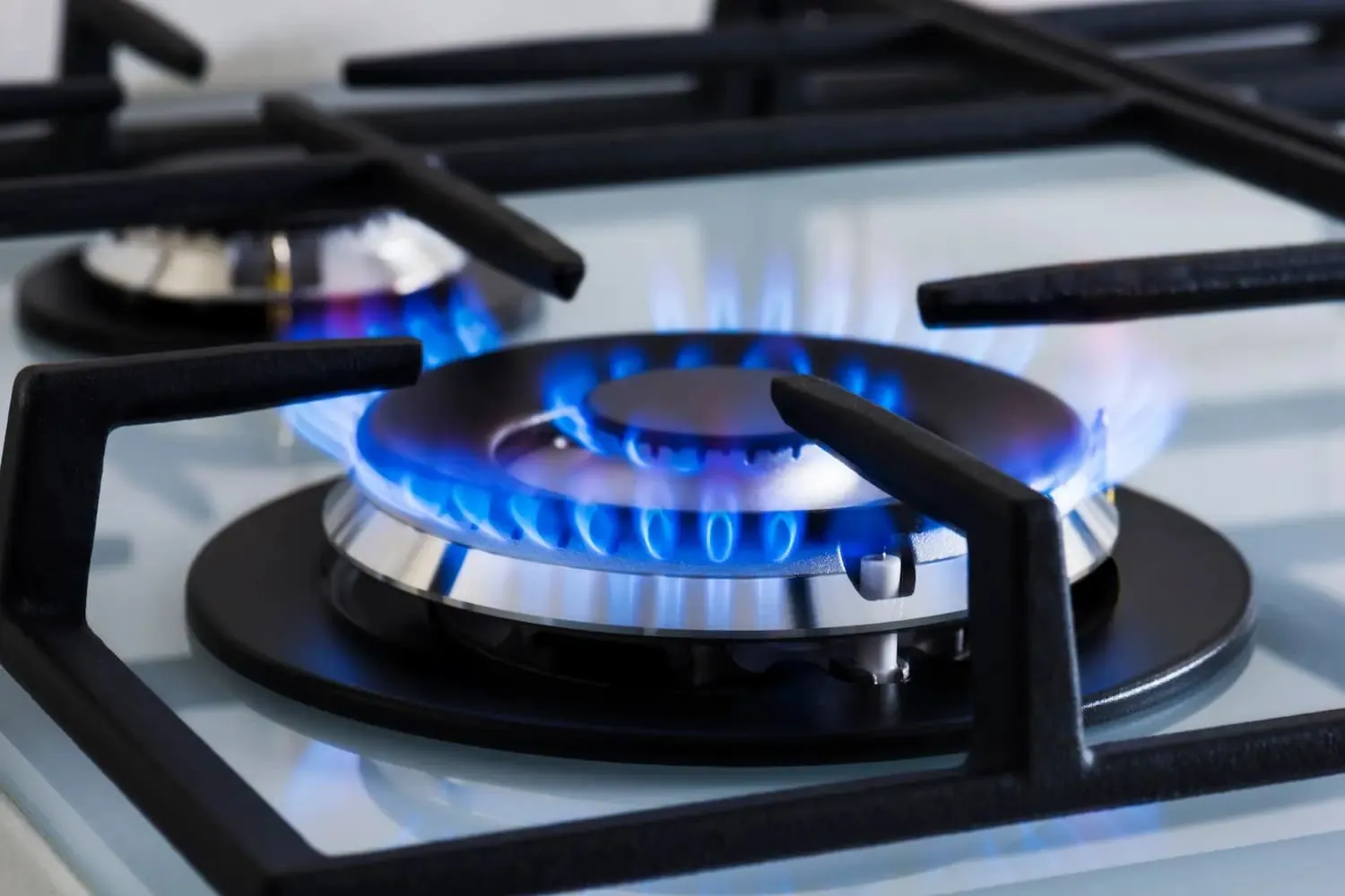 Quemador de una cocina de gas encendido, pieza que se revisa al reparar placas de gas en Valladolid