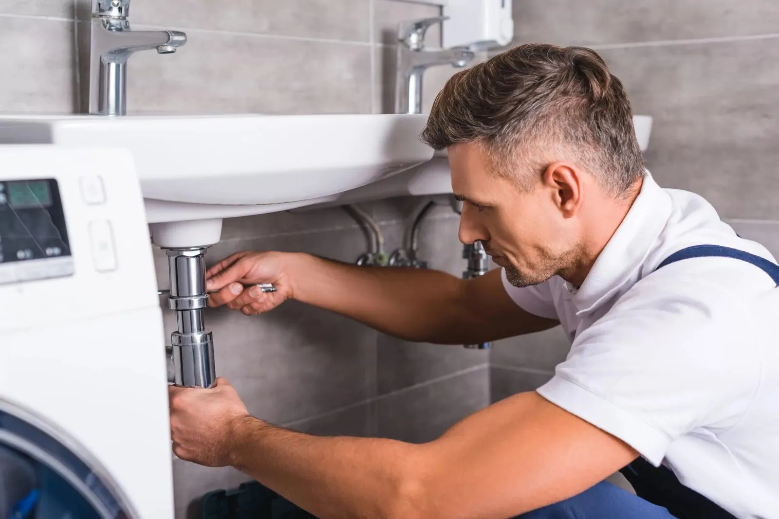 Desatascos: fontanero desmontando el sifón de un lavabo para retirar la obstrucción