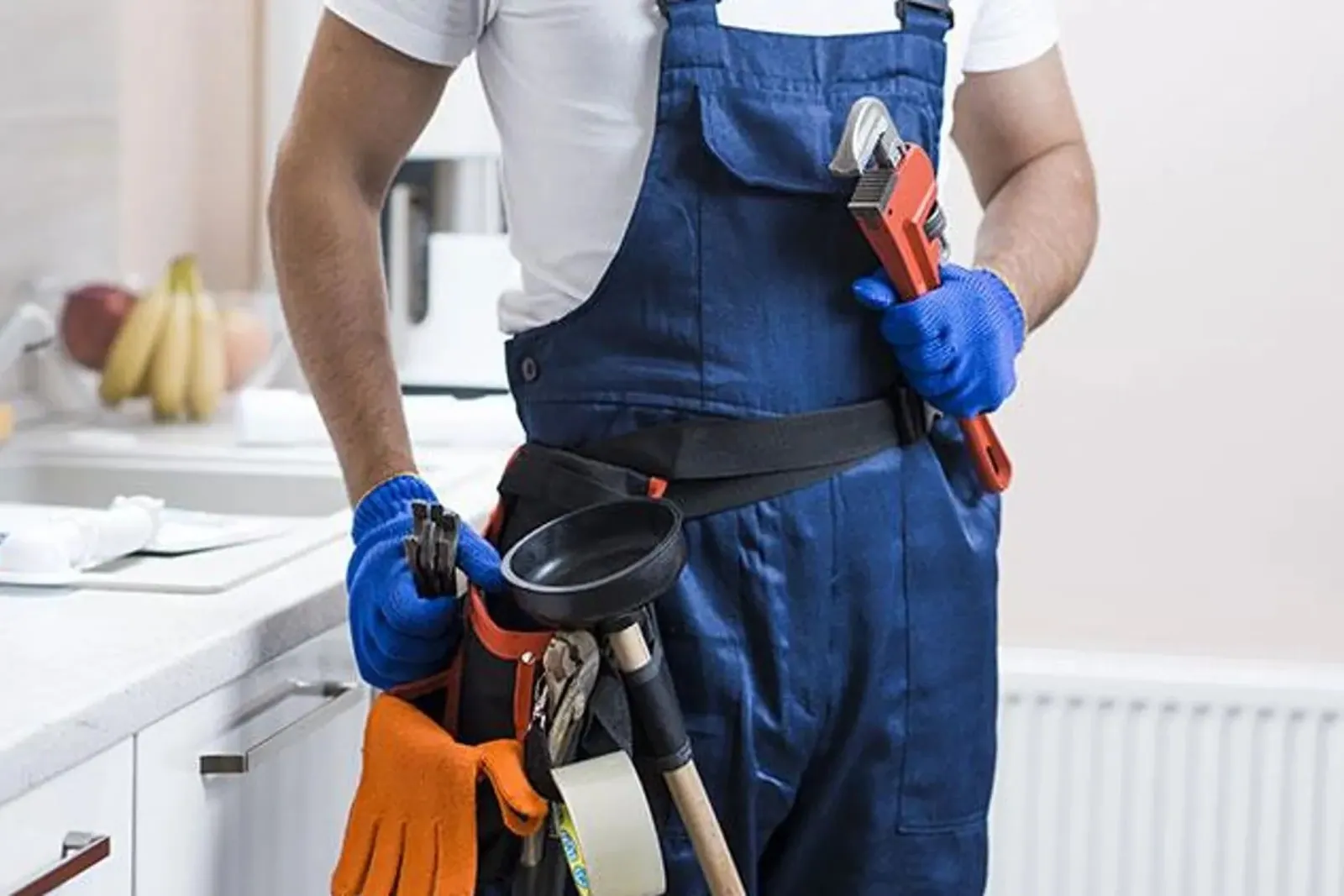 Profesional con cinturón de herramientas en una cocina antes de un desatasco en Málaga