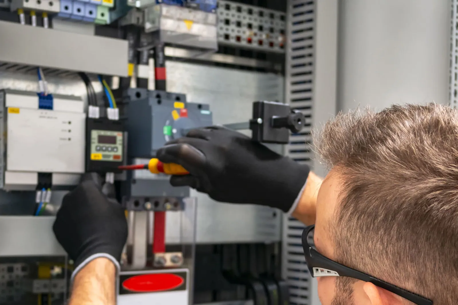 Electricista trabajando en un cuadro de distribución industrial durante una instalación eléctrica