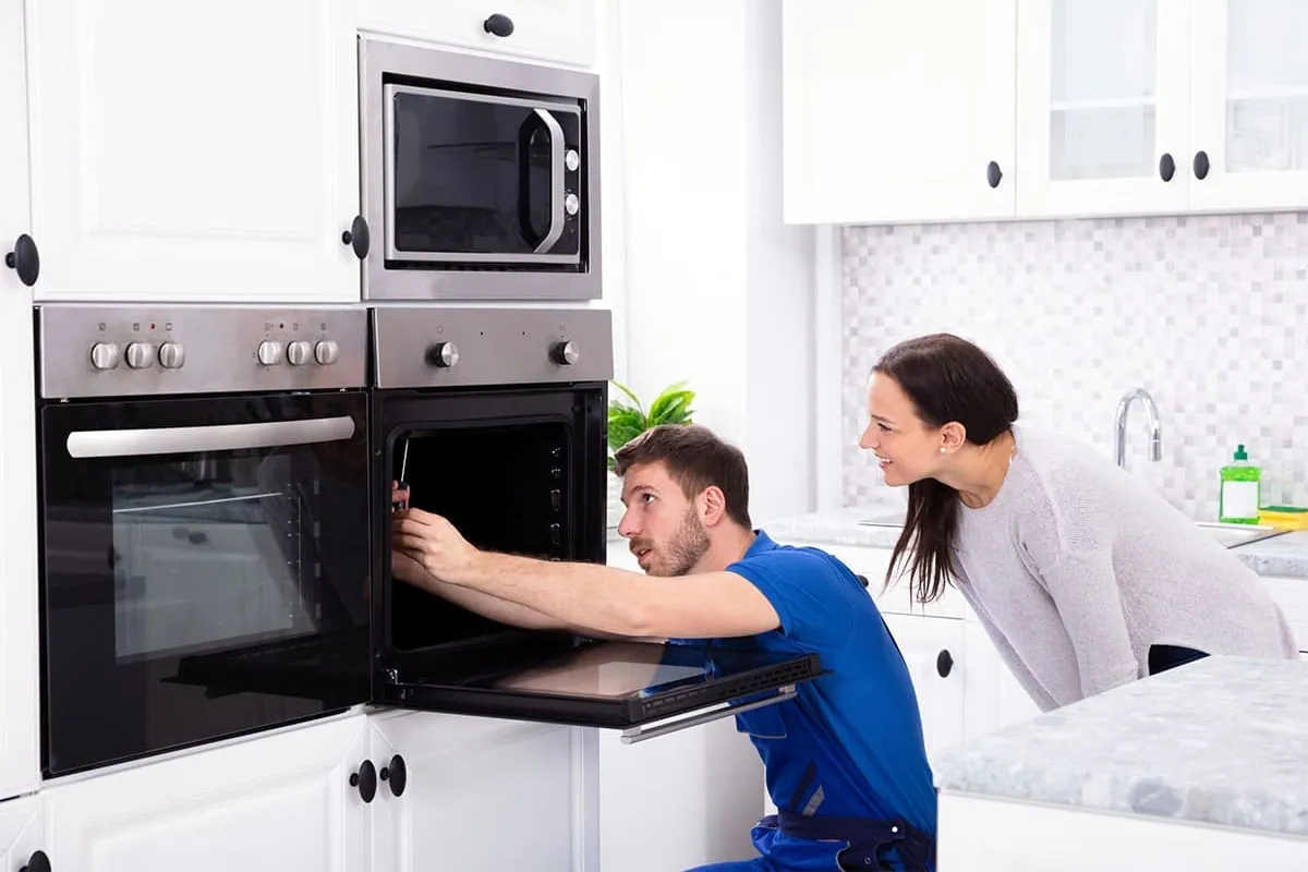 Técnico revisando un horno con la clienta en su cocina