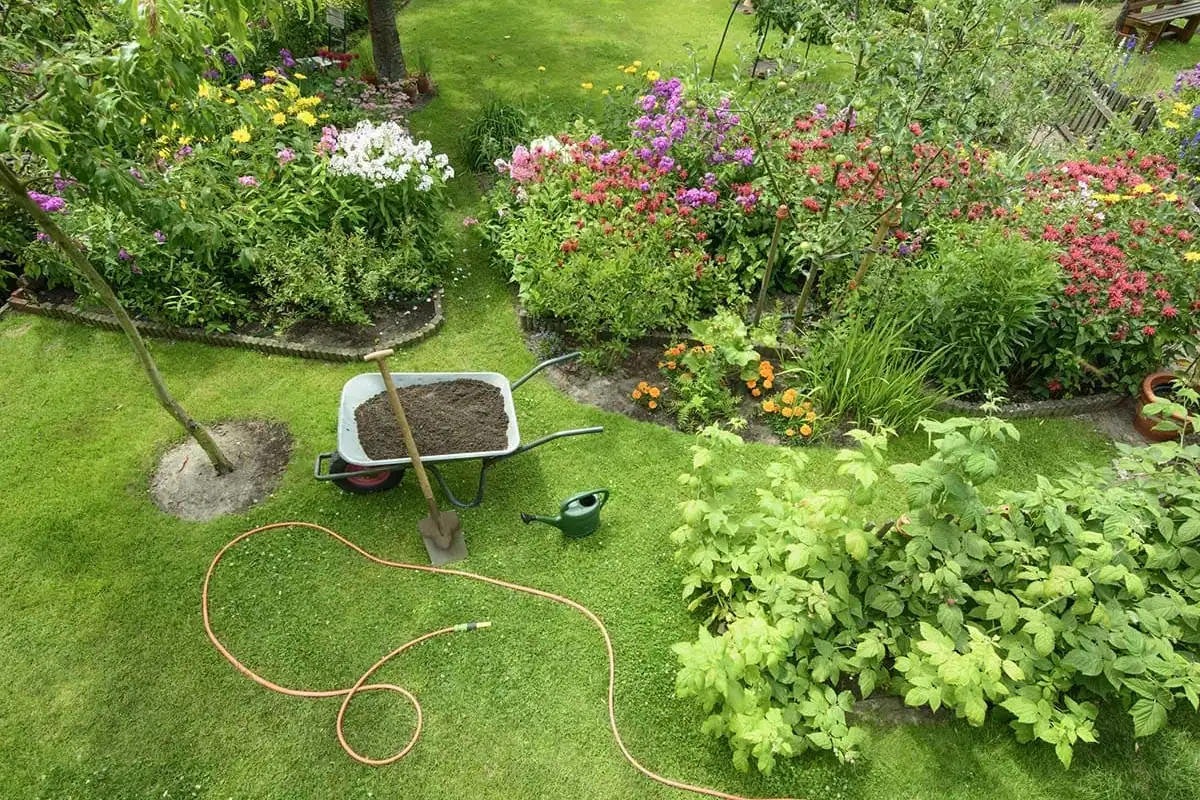 Jardín con parterres de flores y una carretilla durante un trabajo de jardinería