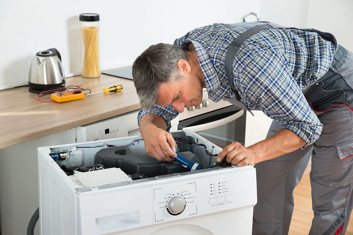 Técnico reparando una lavadora por la parte superior