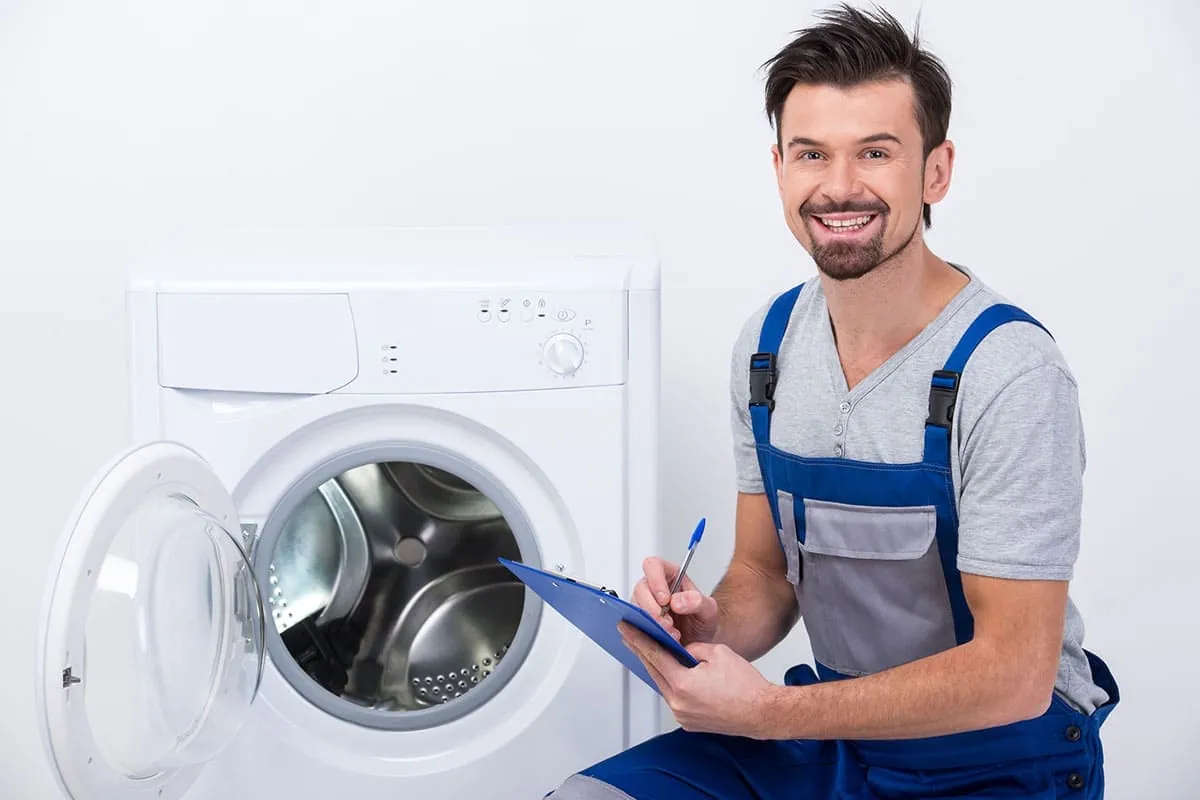 Técnico junto a una lavadora reparada tras su mantenimiento en Oviedo