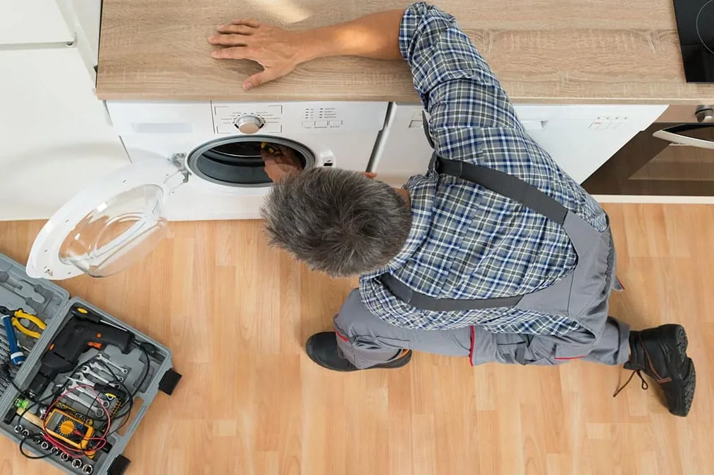Reparación de lavadoras en Oviedo: técnico instalando una lavadora bajo encimera