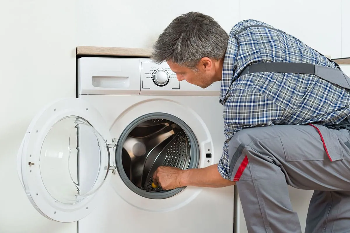 Técnico revisando el tambor de una lavadora de uso intensivo en un negocio de Oviedo