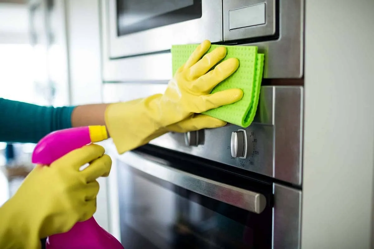 Empresa de limpieza en Elche: profesional con guantes limpiando el interior de un horno