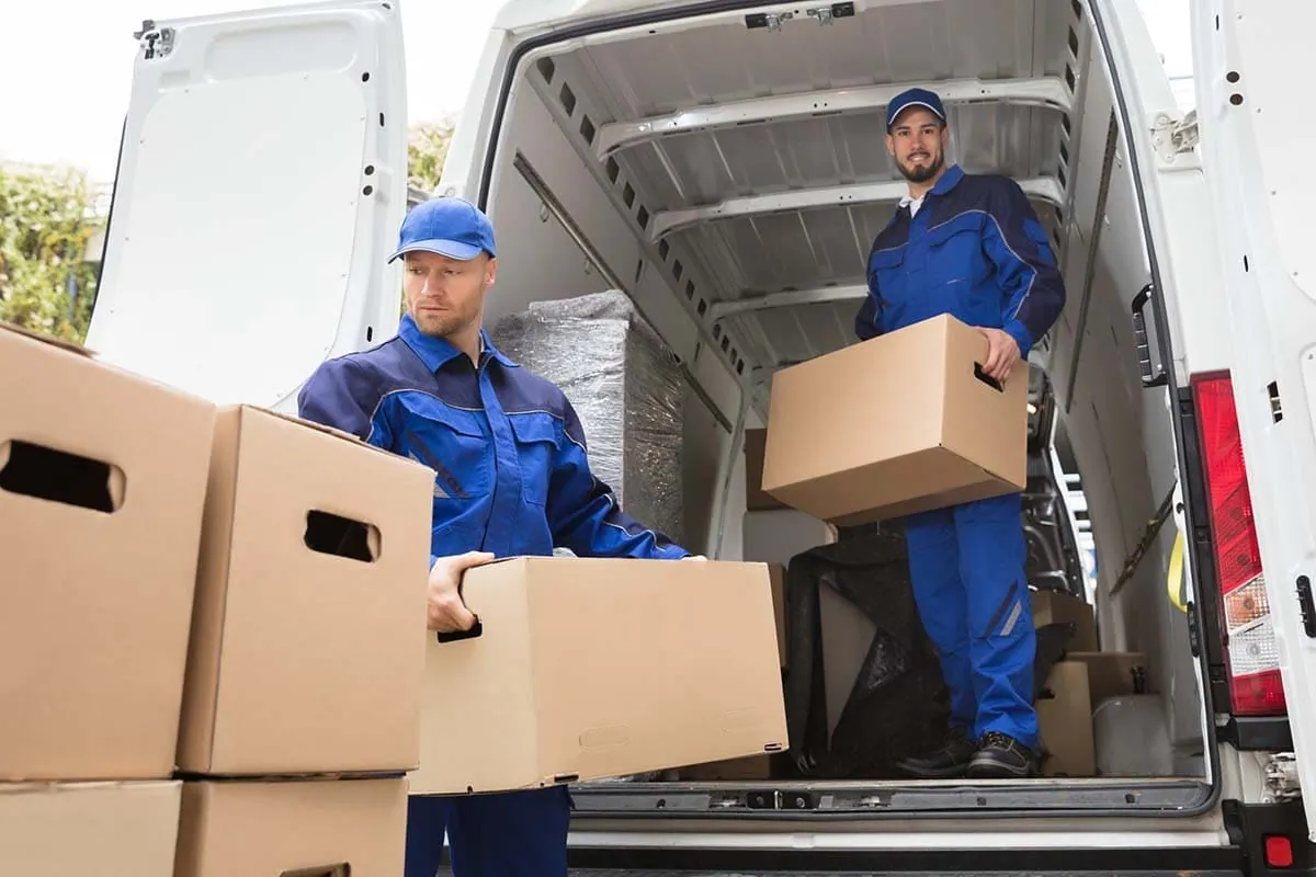 Dos operarios descargando cajas de una furgoneta en un traslado de negocio en Elche