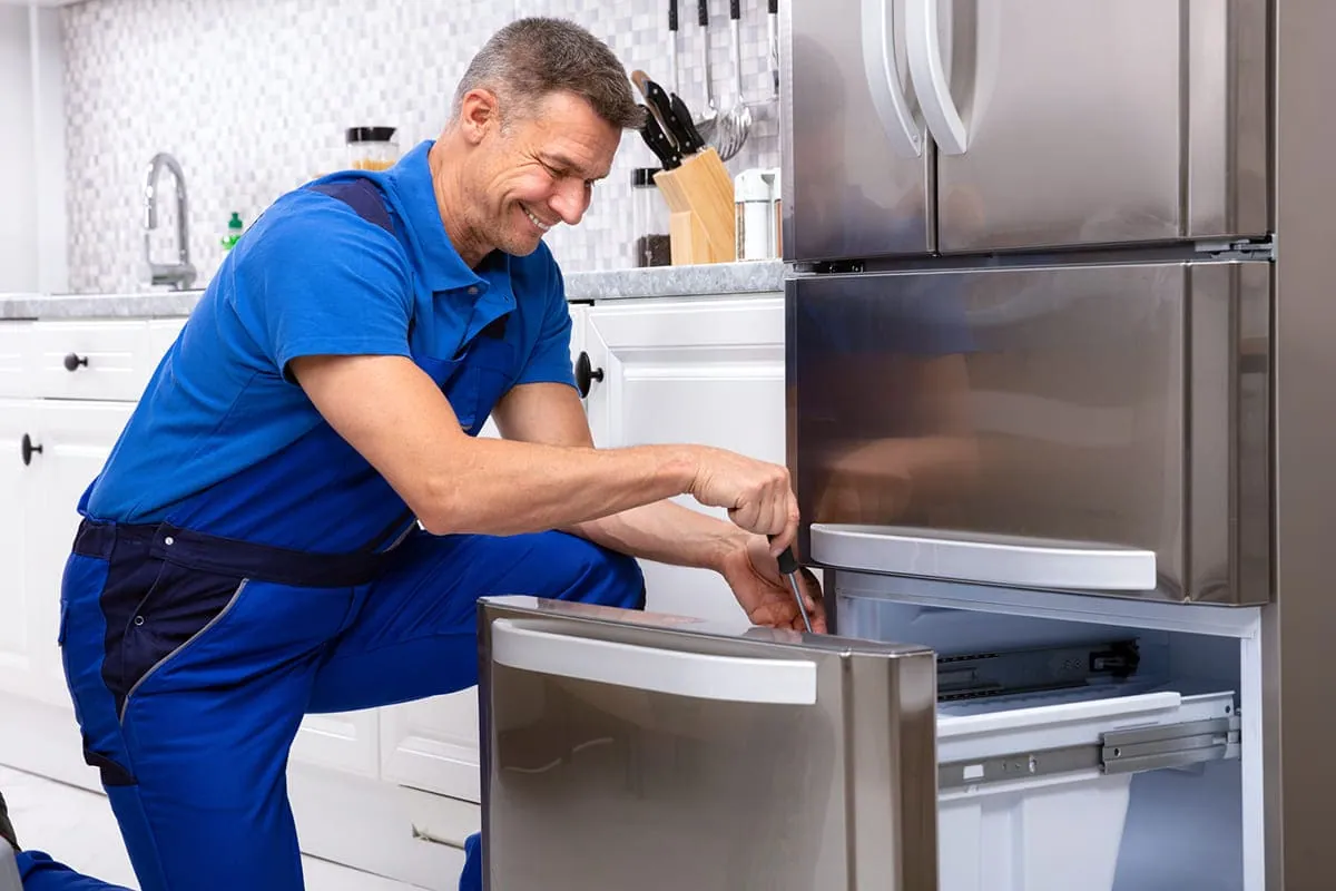 Técnico ajustando el cajón de un frigorífico en el mantenimiento de una nevera en Sevilla