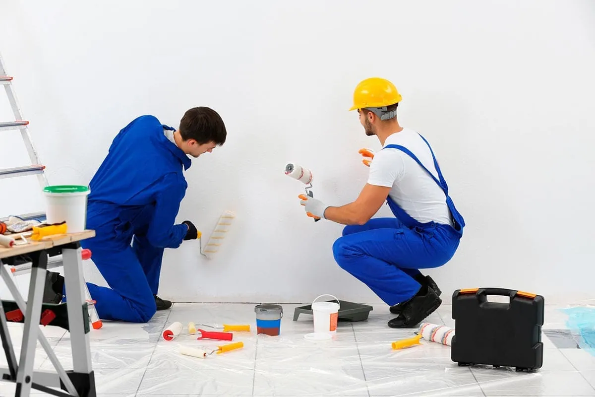 Dos pintores pintando una pared con rodillo en un trabajo de pintura de pisos