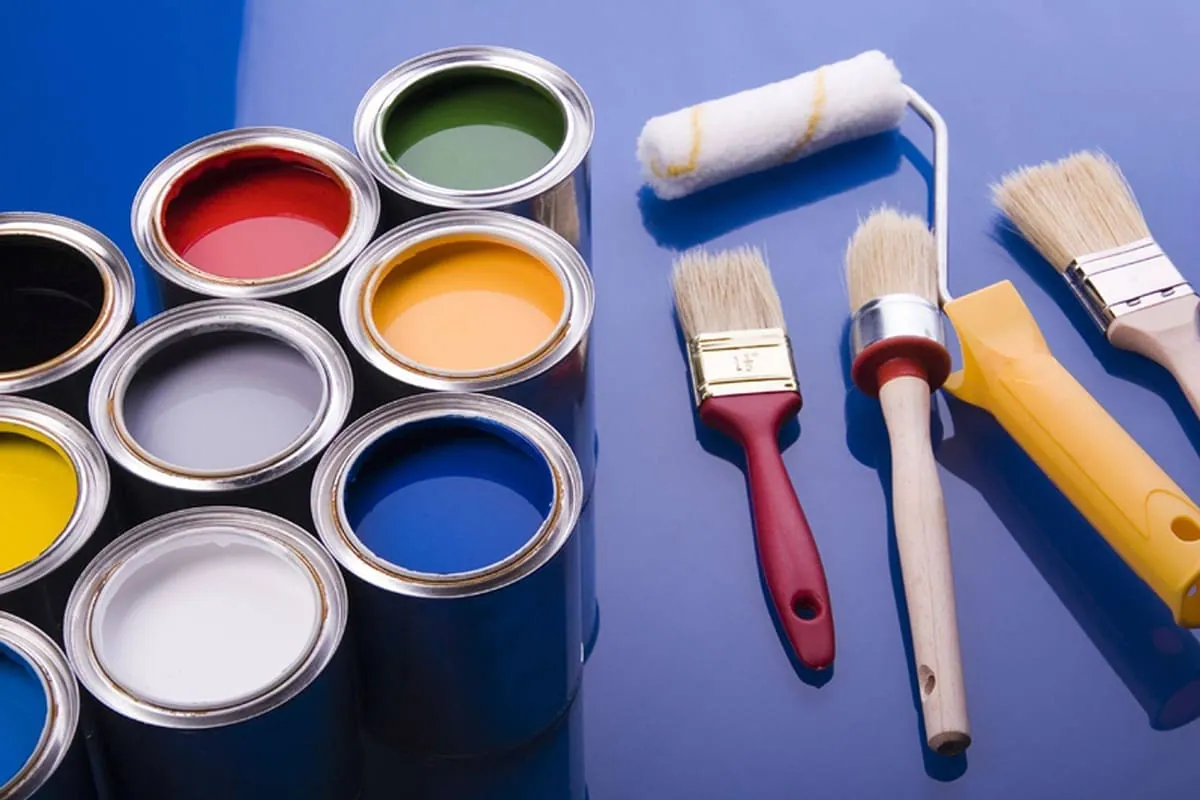 Botes de pintura, brochas y rodillos preparados para pintar un local o una oficina