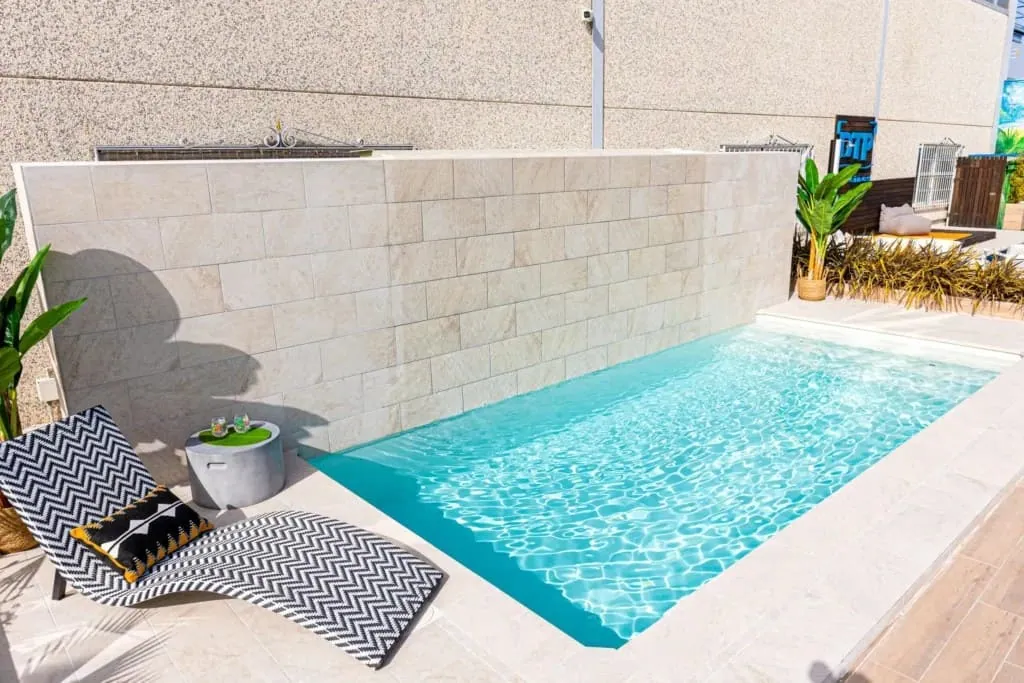 Piscina de obra junto a una terraza, con coronación y playa integradas en la reforma de piscinas