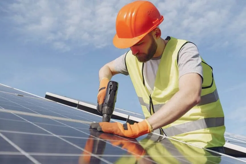 Instalador con casco fijando un panel fotovoltaico durante una instalación de placas solares en Granada