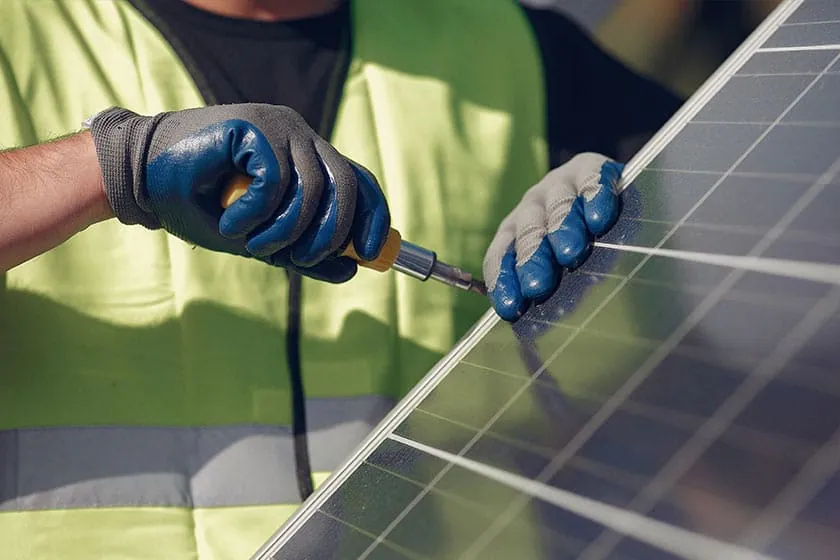 Fijación de un panel solar con guantes de trabajo durante una instalación en Pamplona