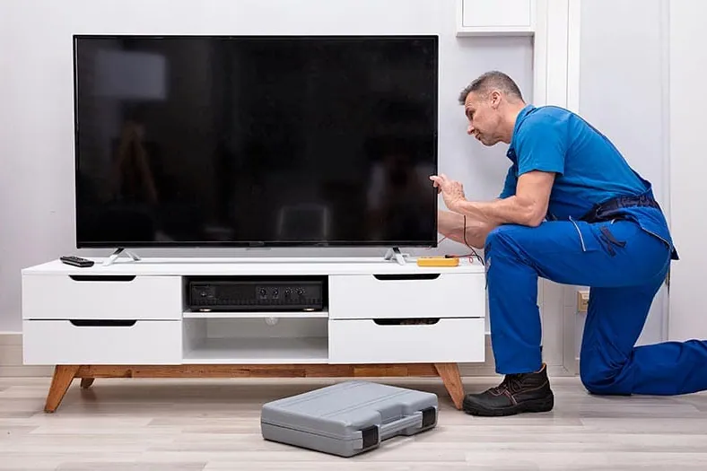 Técnico instalando un televisor en un salón tras la reparación de televisores a domicilio