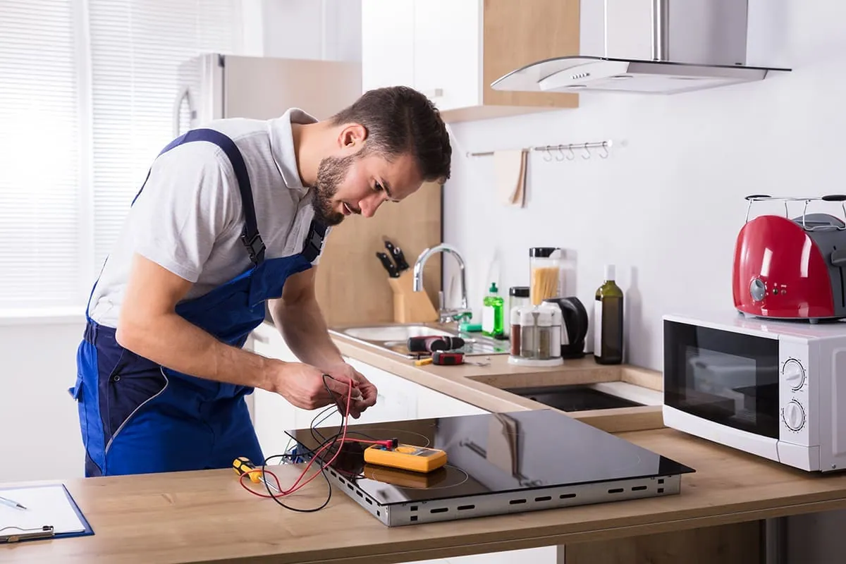 Técnico reparando el interior de una vitrocerámica con las resistencias a la vista
